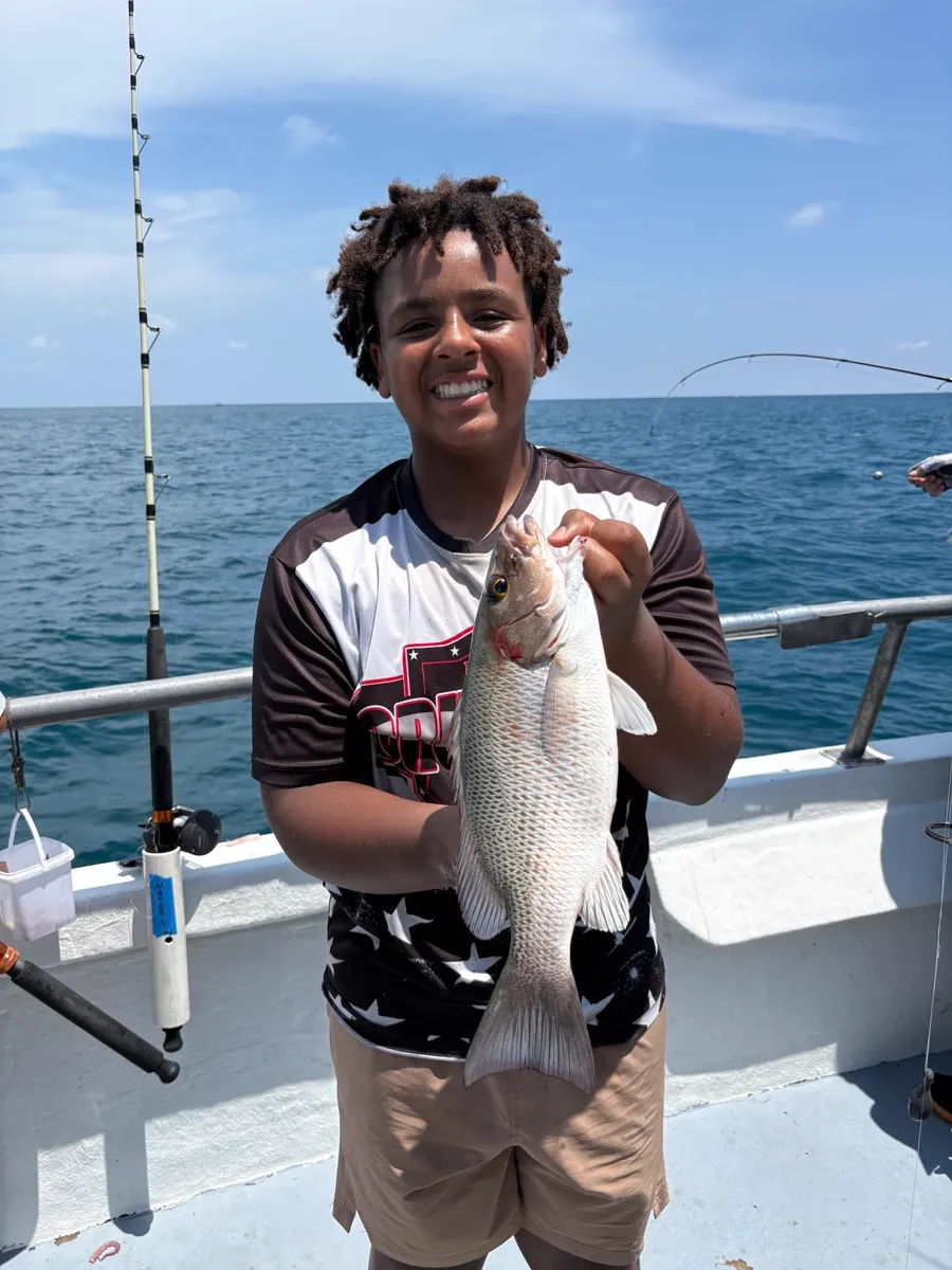 Young angler holding a fish caught aboard the Gulfstream party boat off Key West, June 2026.