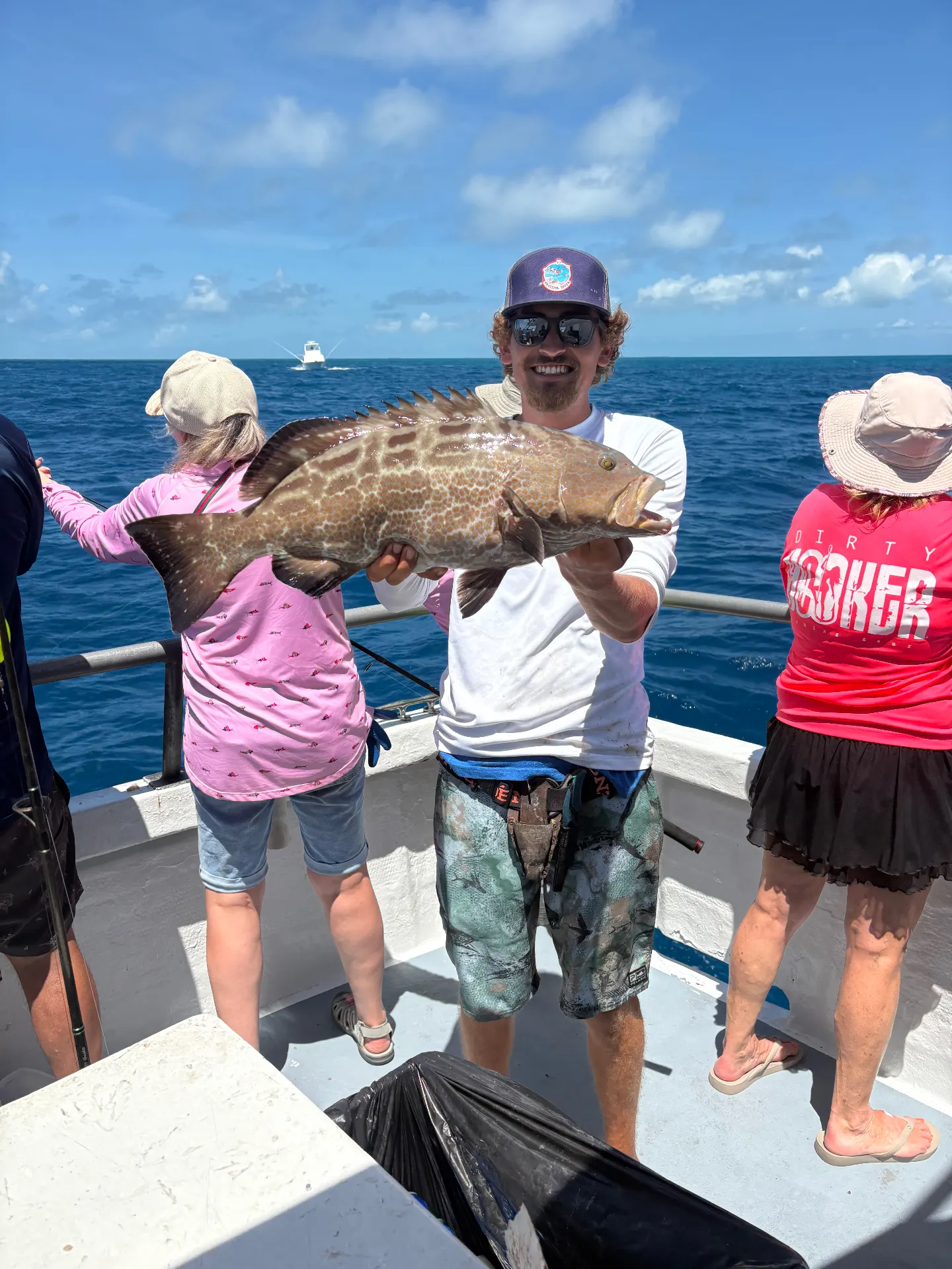 Mate holding a thick black grouper caught and released aboard the Gulfstream party boat off Key West, mid-March 2026.